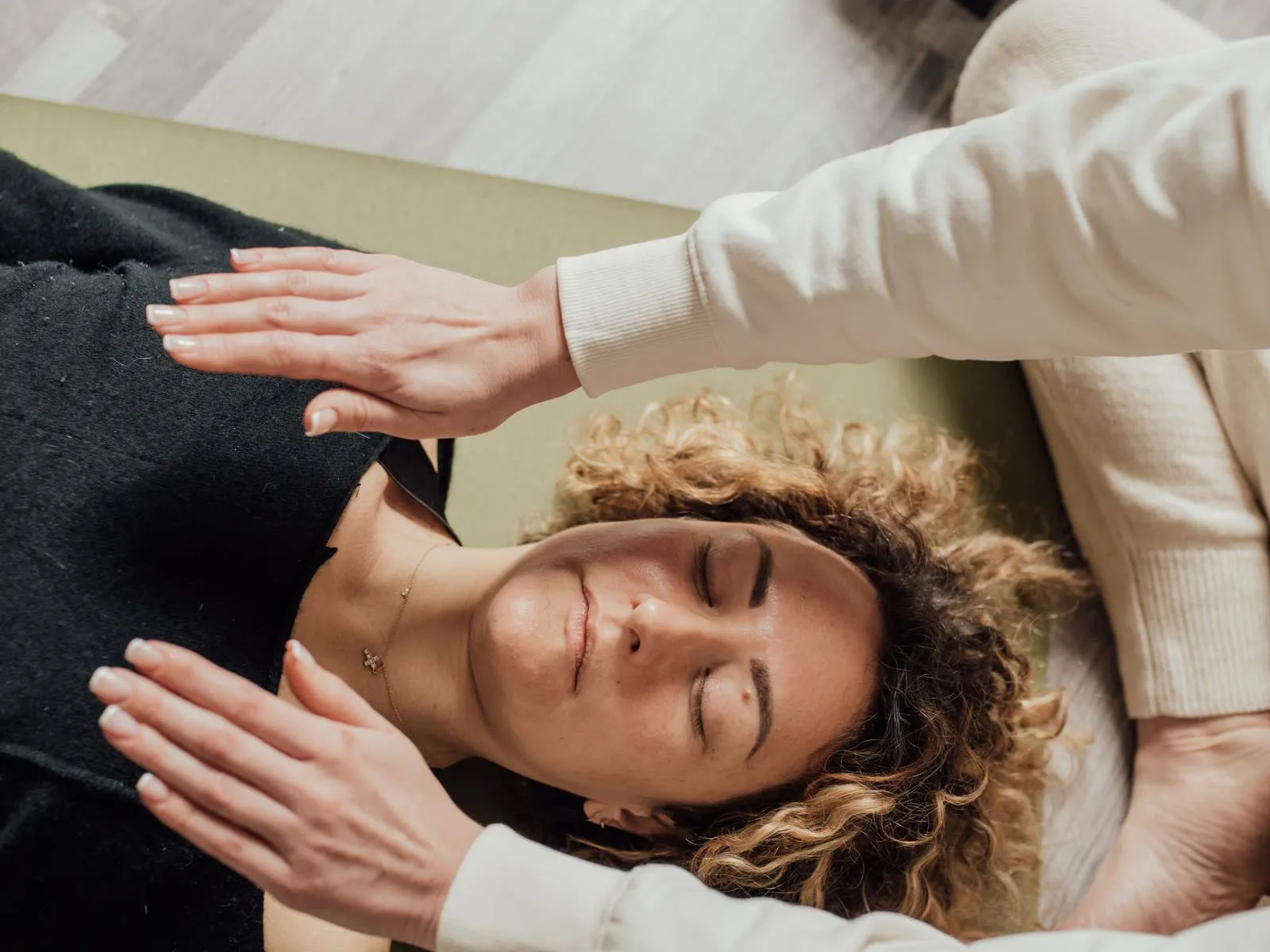 A practitioner's hands hovering above a client's chest and shoulders during a Reiki treatment
